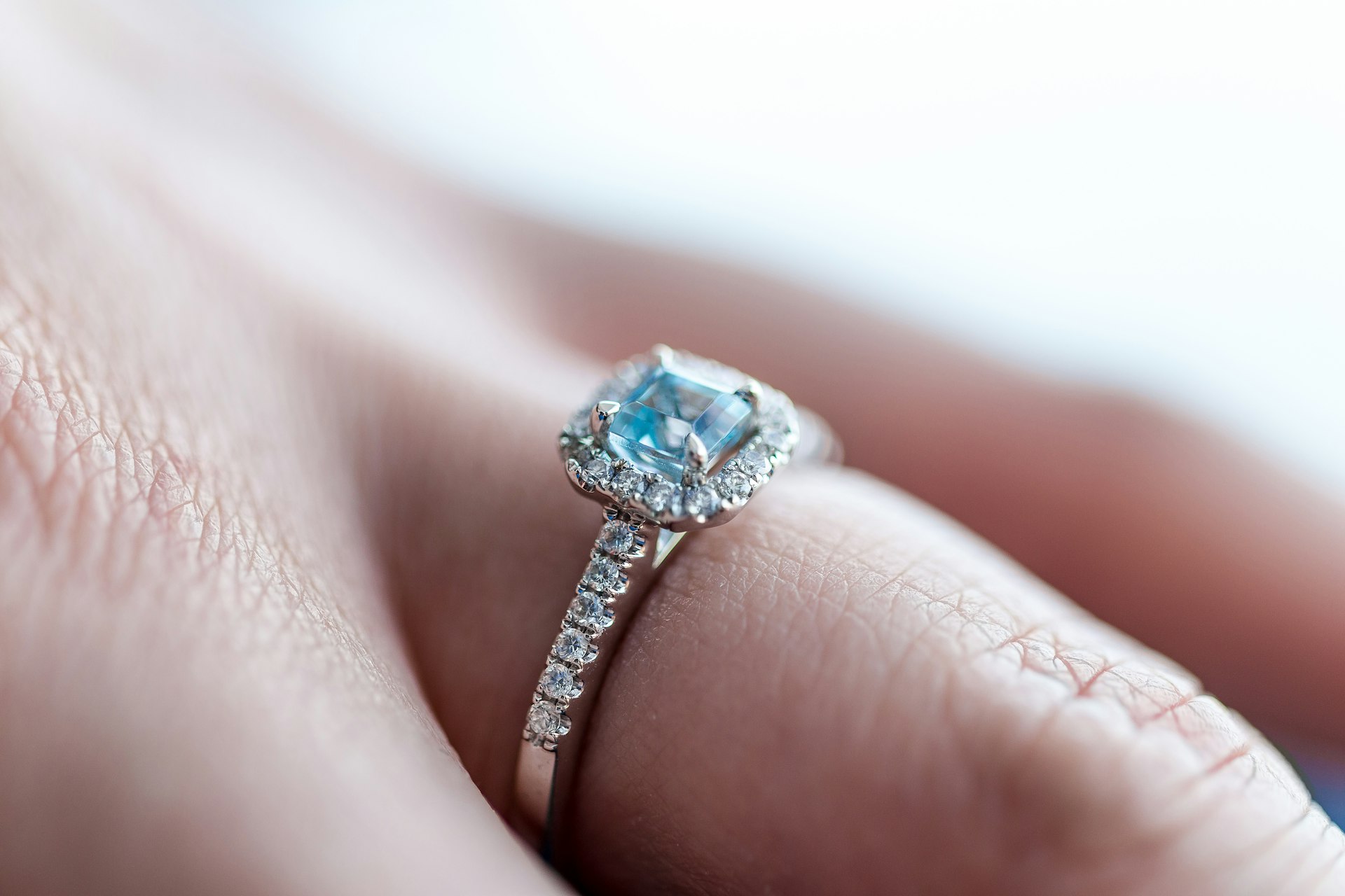 Halo ring with blue topaz gemstone worn on a hand